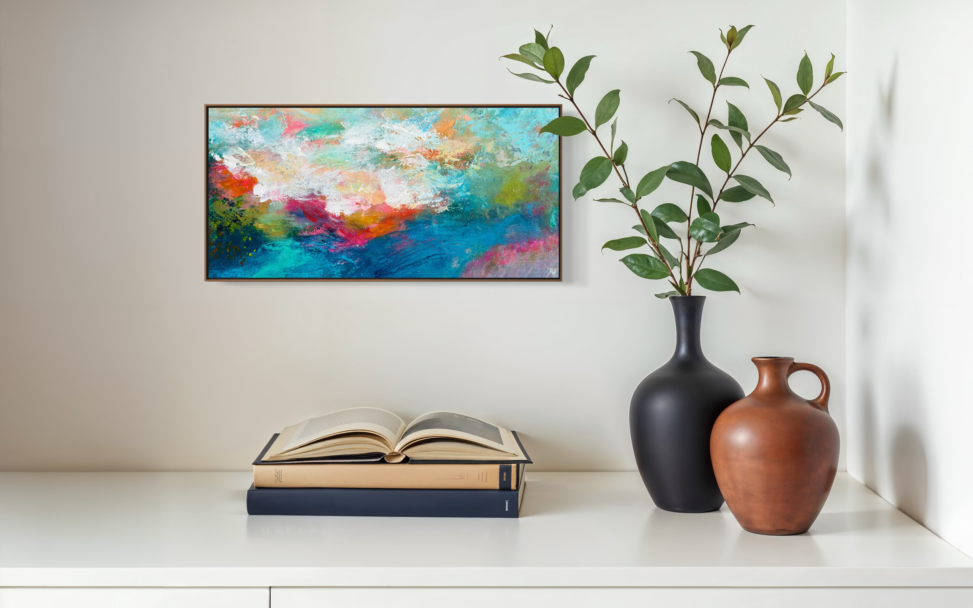 Colorful abstract painting on a wall above an open book with two vases and a plant.